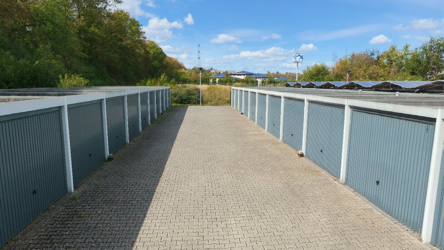 Gepflasterte Fahrgasse zwischen zwei Garagenreihen mit grauen Toren im Garagenpark Kettig